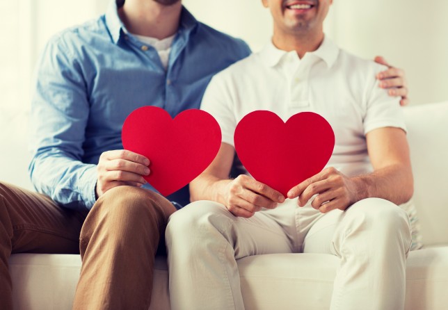 people, homosexuality, same-sex marriage, valentines day and love concept - close up of happy gay male couple with red hearts at home
