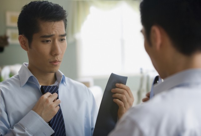 Korean businessman choosing tie in mirror