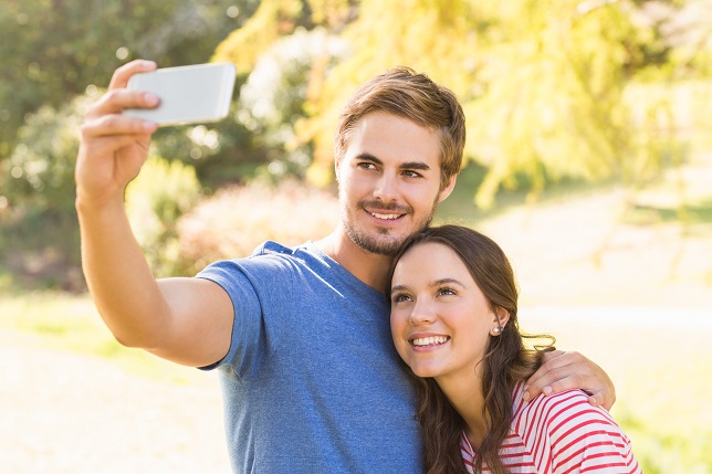 Cute couple doing selfie in the park on a sunny day