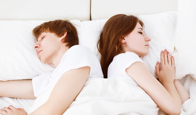 Upset young couple having marital problems a disagreement and sleeping in bed