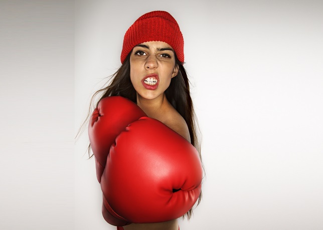 Caucasian woman wearing boxing gloves and hat.