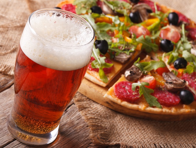 Cold beer and hot pizza with arugula on the table close-up horizontal. rustic style