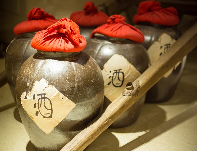 Row of ancient chinese jugs inside with the chinese character for alcohol written on the outside